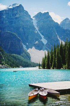 two canoes are docked at the edge of a mountain lake