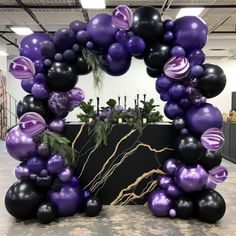 a purple and black balloon arch in an office