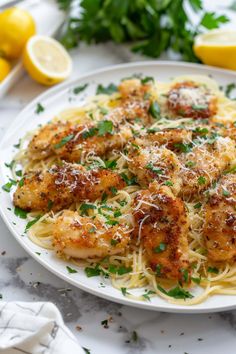 pasta with shrimp and parmesan cheese on a white plate next to lemons