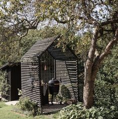 a man sitting on a bench in front of a shed with an open door and grill