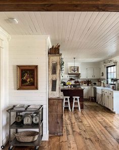 an open kitchen and dining room with wood floors, white walls and ceiling painted in rustic style