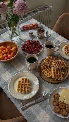 a table topped with waffles, fruit and coffee