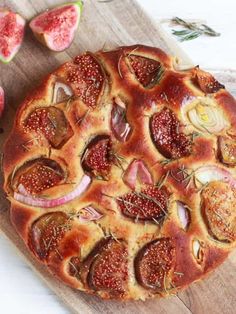 a close up of a pizza on a cutting board with figs and other food