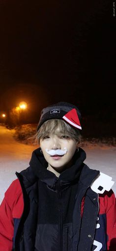 a young man with fake mustaches on his face standing in the snow at night