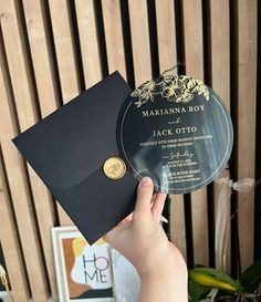 a person holding up a black and gold graduation card