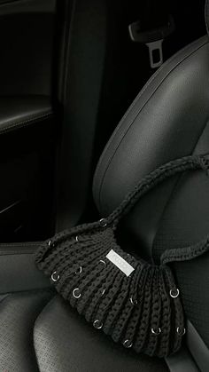 the interior of a car with black leather seats and an arm rest covered in a knitted cover