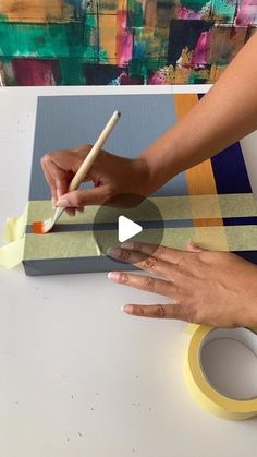 a woman is using tape to paint an abstract painting on canvas with a pencil and brush