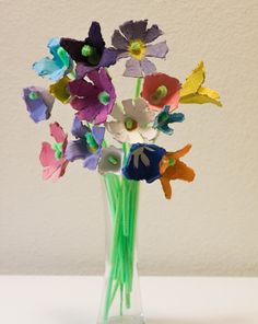 a glass vase filled with colorful flowers on top of a white tablecloth covered floor