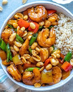 a white bowl filled with shrimp, rice and veggies next to cashews