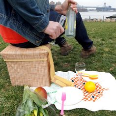 a person sitting on a chair with food and drinks in front of them, near a body of water