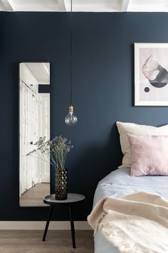 a bedroom with blue walls and white bedding has a plant on the end table