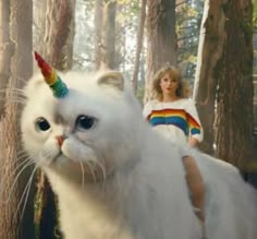 a woman riding on the back of a white cat with a rainbow colored horn and tail