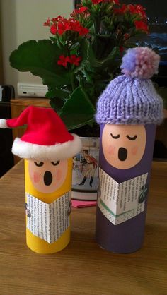 two paper dolls are sitting next to each other on a table with flowers in the background