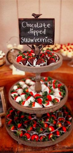 three tiered trays filled with chocolate dipped strawberries and topped with small candies