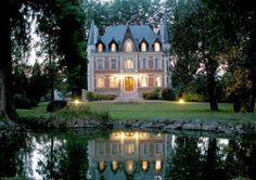 a large house sitting on top of a lush green field next to a lake at night