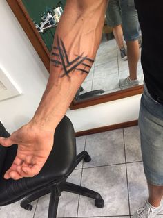 a man with a tattoo on his arm sitting in front of a mirror