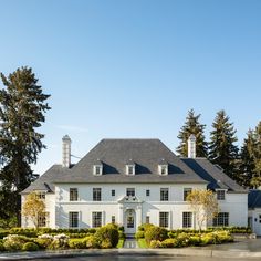 a large white house surrounded by trees and bushes