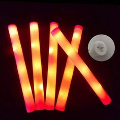 five glowing sticks are lit up in the dark, with one light on it's side