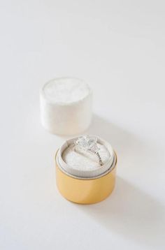 a yellow container with a ring on it sitting next to a white box filled with something