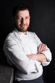 a man wearing a chef's coat and standing with his arms crossed in front of him