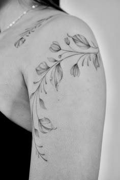 black and white photo of woman's back shoulder with leaves tattoo design on it