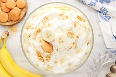 a banana pudding in a glass bowl next to some cookies and bananas