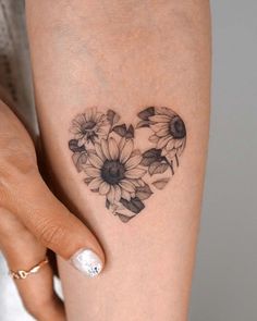 a woman's arm with sunflowers in the shape of a heart