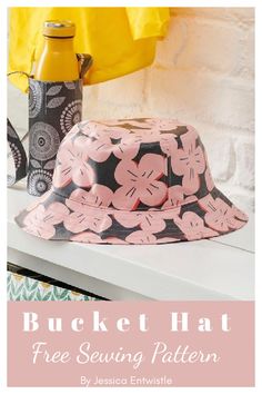 a bucket hat sitting on top of a white table next to a bottle and yellow shirt