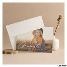 a card with a photo on it next to a small white vase and dried flower