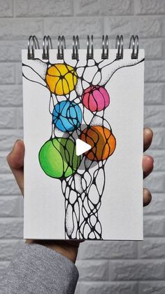 someone is holding up a drawing with colored balls on it