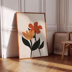 an orange flower sitting on top of a wooden floor in front of a white wall