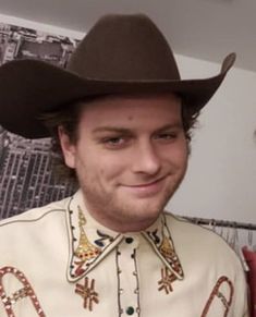 a man in a cowboy hat smiles at the camera