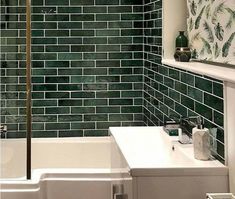 a bathroom with green tiles on the walls and floor, including a white bathtub