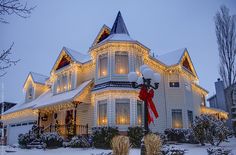 a large house with christmas lights on it's windows and decorations around the porch