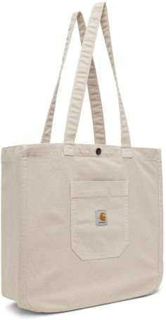 Heavyweight stone-dyed cotton twill tote in beige. · Fading throughout · Fixed carry handles · Patch pocket and logo patch at face · Press-stud closure · Zip pocket at interior · Unlined · H15 x W15.5 x D5.5 Supplier color: Tonic Carhartt Work In Progress, Bag Suitcase, Denim Tote, Brown Shoulder Bag, Carhartt Wip, Baby Body, Work In Progress, Cotton Tote Bags, Patch Pocket