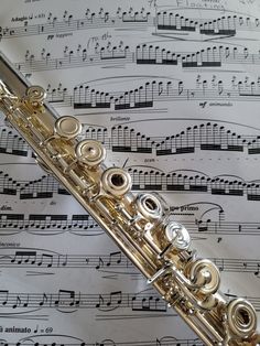 a flute is sitting on top of sheet music with musical notations in the background