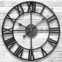 a black clock on a brick wall with roman numerals in the face and hands