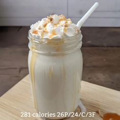 a glass jar filled with whipped cream and caramel on top of a wooden cutting board