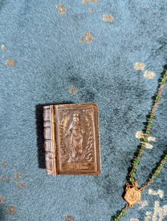 an old book is laying on the floor next to a beaded necklace and bracelet