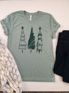 Christmas Shirt. Womens Christmas Shirt. Christmas Tree Tee. Christmas T-Shirt. Christmas Tees. Holiday Shirts. Christmas Graphic Tee. Everyone needs a favorite tee. This tee can be just that. This one has a cute tree design on a heather dusty blue colored tee with a dark green ink. It's soft, comfortable, and stylish. Grab one for yourself or your friend who loves Christmas! Christmas Tree Tee Bella/Canvas brand Unisex Fitted Tee, 4.2 oz 100% Combed and ringspun cotton The tee is heather dusty Cute Tree, Womens Christmas Shirts, Tee Tree, Womens Christmas, Christmas Graphic, Fitted Tee, Tree Design, Christmas T Shirt, Christmas Tees