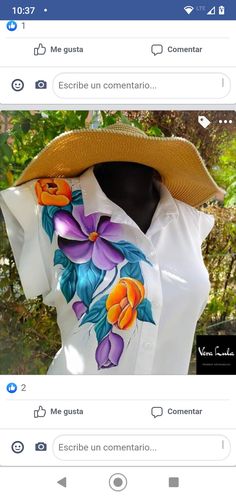 a woman's white shirt with colorful flowers on it and a straw hat over her head