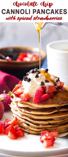 a stack of chocolate chip cannoli pancakes with whipped cream and strawberries on top