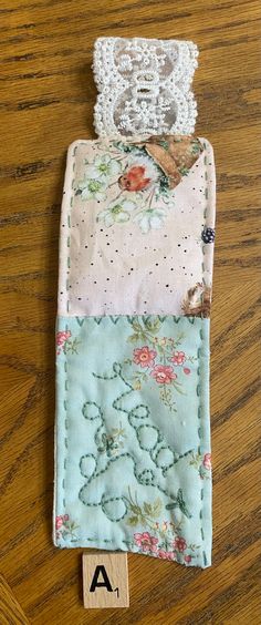 a piece of fabric with flowers and lace on it sitting on top of a wooden table