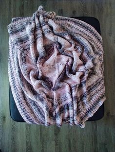 a blanket is laying on top of a black chair with wood flooring in the background