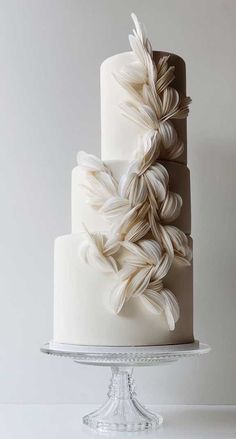 a three tiered cake with white icing and leaves on top