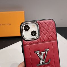 a person holding up a red louis vuitton iphone case with diamonds on it