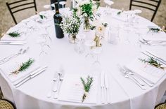 the table is set with white linens and silverware for an elegant wedding reception