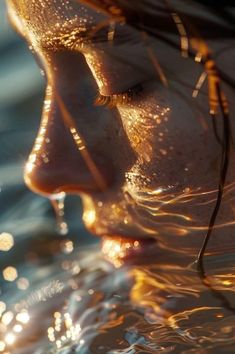 a close up of a woman's face in the water with sun shining through her hair