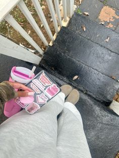 a person sitting on a porch with their feet up and holding a book in front of them