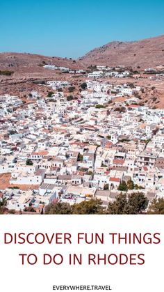 Aerial view of a hillside town in Rhodes with white buildings and brown landscape.